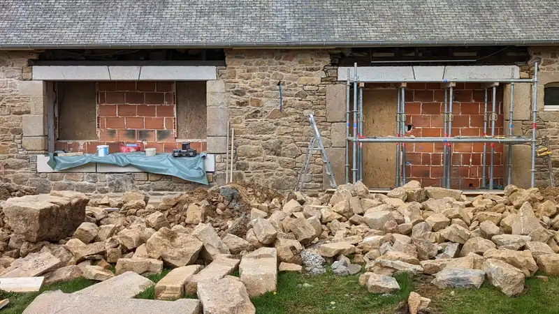 Façade en pierre en cours de reprise, jambages et linteaux en granit